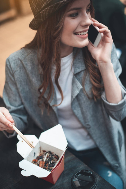 Cheerful lady is chatting on phone while eating - Foto, Imagem