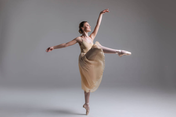 Baila para inspirar! Vista lateral completa de la bailarina de ballet clásica realizando movimientos de ballet sobre un fondo aislado
. - Foto, imagen