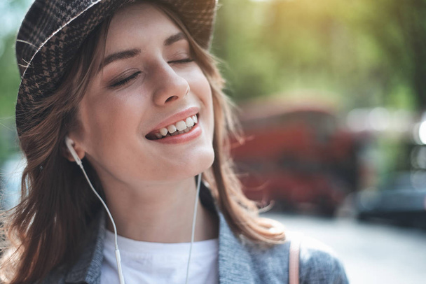 Красивая молодая леди слушает музыку с усмешкой
 - Фото, изображение
