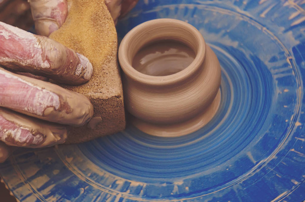 Potters hands shaping a bowl out of clay. Man cleans with sponge pottery on a Potter's wheel. The final stage of manufacture of the jug - Photo, Image