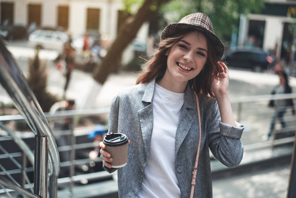 Young smiling lady standing outside with hot drink - Фото, изображение