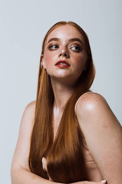 Portrait of a beautiful girl with long hair, makeup and freckles - Fotografie, Obrázek