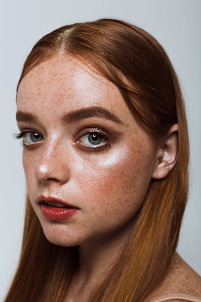 Portrait of a beautiful girl with long hair, makeup and freckles - Фото, изображение