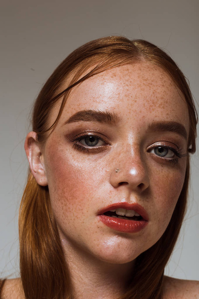 Portrait of a beautiful girl with long hair, makeup and freckles - 写真・画像