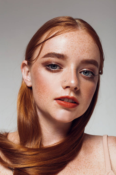 Portrait of a beautiful girl with long hair, makeup and freckles - Fotó, kép