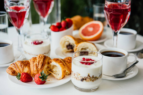 Healthy breakfast served with black coffee, croissant, muesli and fruits - 写真・画像