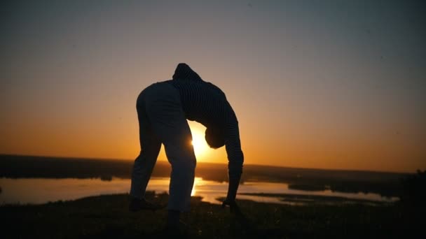 Acrobat usnadňuje torzní na ruce, západ slunce, slow-motion - Záběry, video