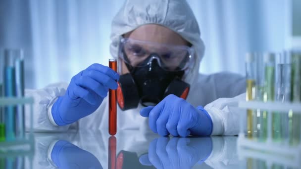 Scientist in gas mask holding test tube with dangerous substance, biohazard - Materiał filmowy, wideo