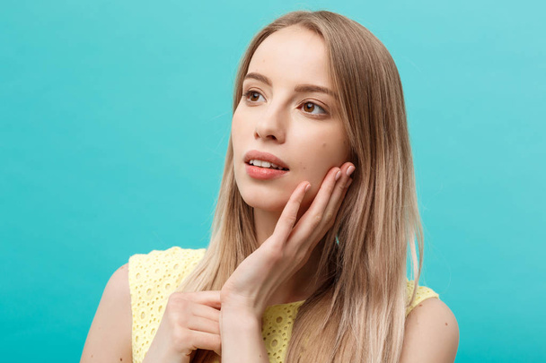 Beautiful young woman with clean perfect skin. Portrait of beauty model touching her face. Spa, skincare and wellness. Close up, blue background, copyspace. - Φωτογραφία, εικόνα