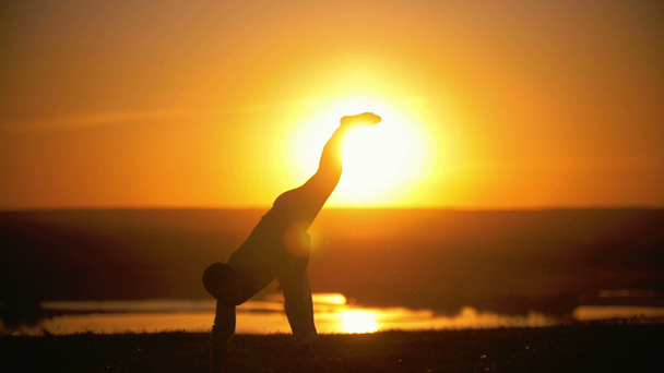 O desportista está envolvido na capoeira no fundo de um pôr-do-sol laranja, em câmera lenta
 - Filmagem, Vídeo