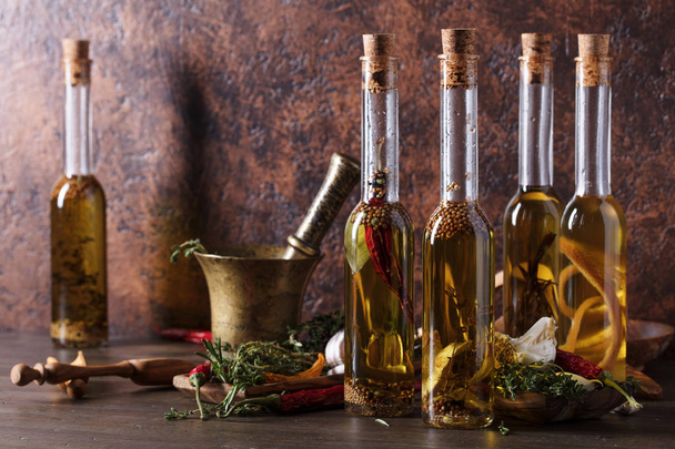 Bottiglie di olio d'oliva su un vecchio tavolo di legno. Olio di oliva con diverse spezie ed erbe aromatiche. Copia spazio
. - Foto, immagini