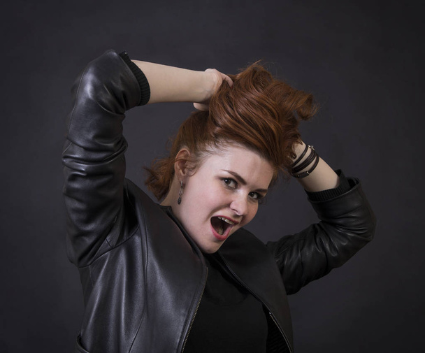 Emotional brunette posing in the Studio in a leather cloak.Isolated image on a dark background. - Foto, imagen