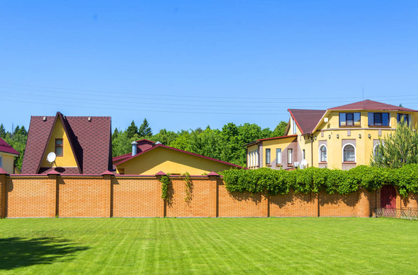 Belle maison de campagne avec garage derrière une clôture en brique
. - Photo, image