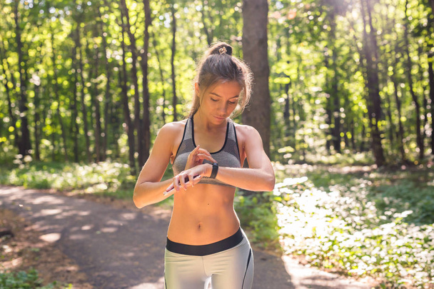 Vrouw met behulp van activity tracker of hartslagmeter. Outdoor fitness concept. - Foto, afbeelding