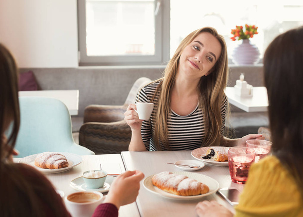 Щасливі жіночі сфінкси п'ють каву і спілкуються в кафе
 - Фото, зображення