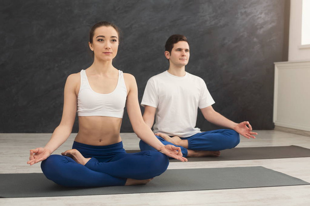 Młoda para Praktykuje jogę siedzi w padmasana - Zdjęcie, obraz