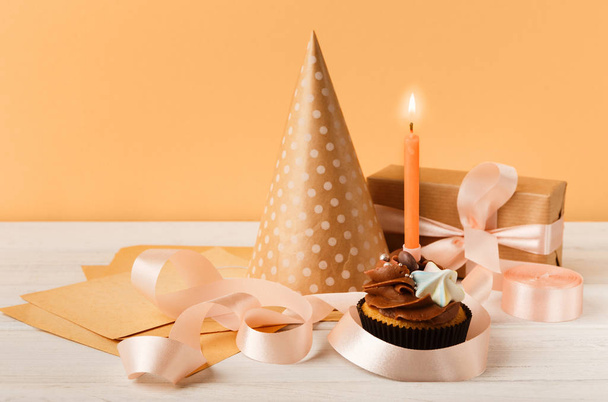 Delicious cupcake and gift on yellow background - 写真・画像