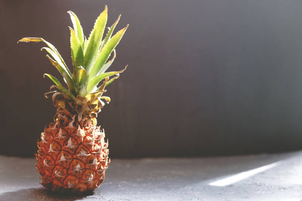 Ripe juicy pineapple on gray wooden table, backlight. With copy space - Фото, изображение