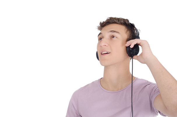 Portrait of smiling teen listening music with headphones. Isolated white background - Foto, imagen