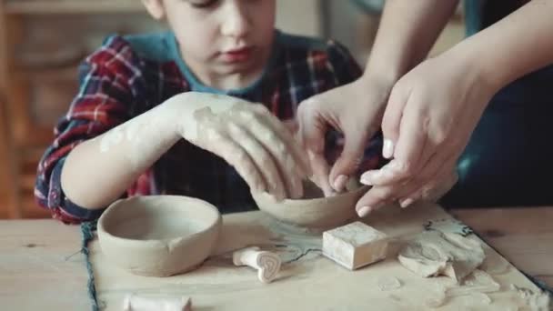 little girl making a plate of clay. The teacher helps the child with the task - Footage, Video