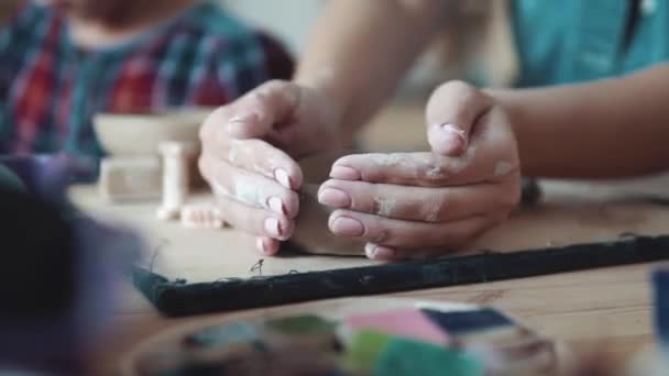 het creëren van een plaat van klei. een meisje met mooie handen beeldhouwt een odd job op een aardewerk-les - Video