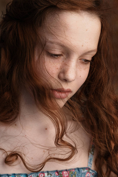 Dramatic portrait of a young cute redhead teenage girl with curly haircut in the studio - Fotoğraf, Görsel
