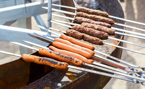 Gustose salsicce che cuociono sopra i carboni ardenti su un fuoco barbecue
 - Foto, immagini
