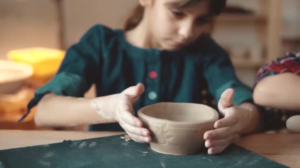Kind bastelt einen Teller aus Ton. eine Lektion in Töpfern. Kleines Mädchen fertigt Muster auf einem Tonstempel - Filmmaterial, Video