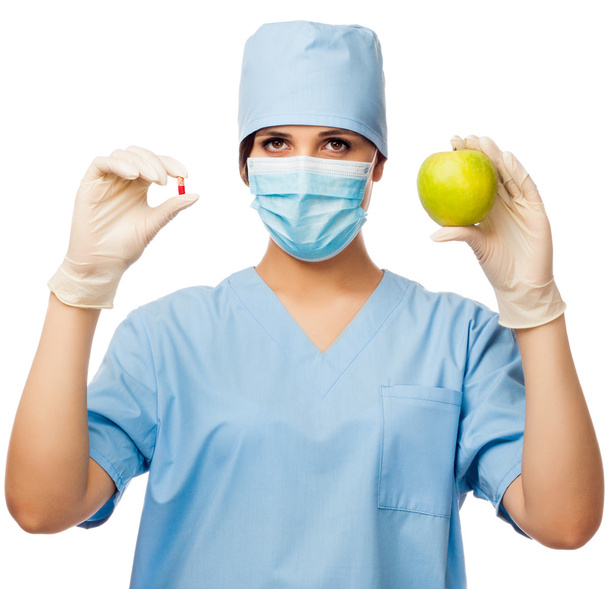 Young doctor holding pill and apple - Foto, imagen