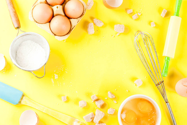Ingredients and utensils for cooking baking egg, flour, sugar, whisk, rolling pin, on bright yellow background, copy space top view frame - Photo, Image