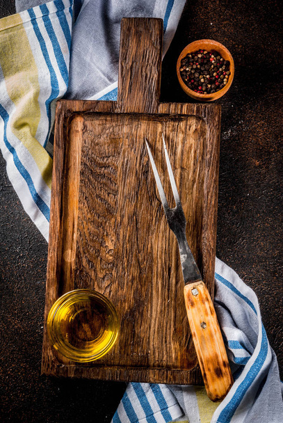 Vieille planche à découper avec fourchette à découper, herbes et épices sur fond bois foncé vue de dessus
 - Photo, image