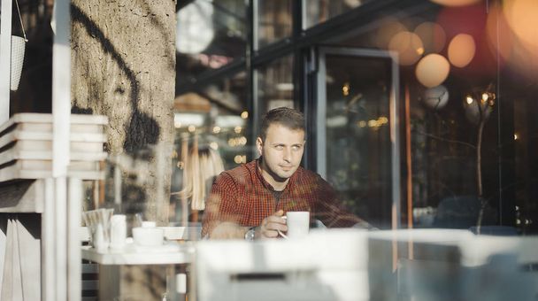 Young attractive man drinking coffee at lunch time - 写真・画像