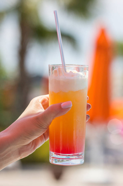 Delicious fresh cocktail in the girl's hand next to the pool, close-up - Φωτογραφία, εικόνα