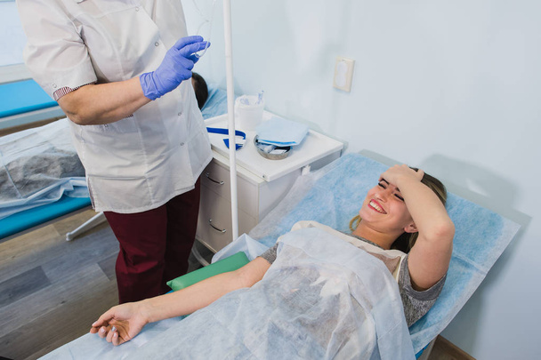 Επαγγελματίας νοσοκόμα κάνει μια ένεση με μια γυναίκα ξαπλωμένη στο χειρουργικό τραπέζι στο νοσοκομείο προετοιμασία έννοια αναισθητικό ιατρική χειρουργική επέμβαση για υγειονομική περίθαλψη. - Φωτογραφία, εικόνα