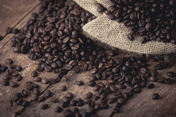 Sacco di chicchi di caffè fresco rovesciato su sfondo marrone
 - Foto, immagini