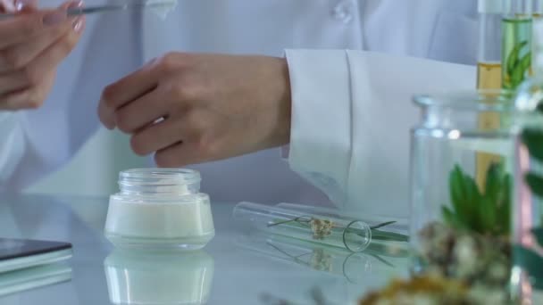Cosmetology expert puts cream on her hand and typing observations in e-journal - Záběry, video