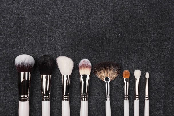 row of different makeup brushes in white covering - Фото, изображение