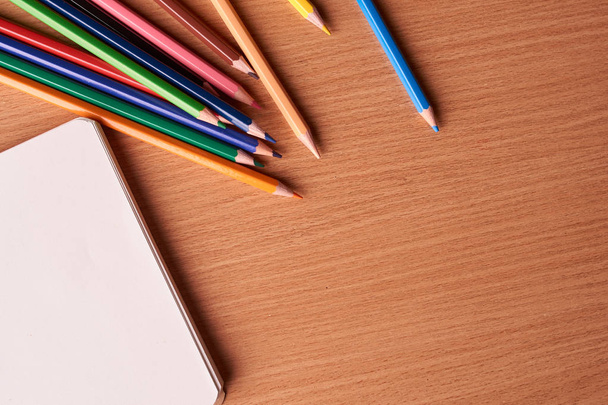 Notitieblok openen op houten achtergrond met kleurrijke potloden. Plat leggen - Foto, afbeelding