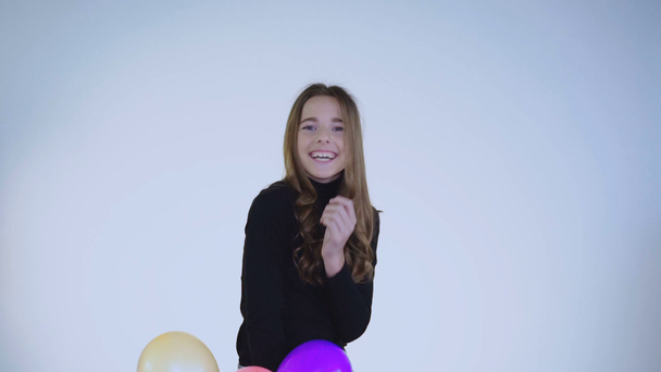 Surprised girl catches balloons and plays with smile on face - Záběry, video