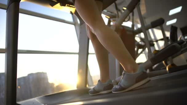 Female legs running on gym treadmill, sport woman warming up before workout - Materiał filmowy, wideo