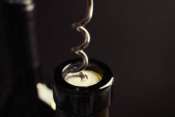 Opening bottle of wine with corkscrew on dark background, closeup - Fotoğraf, Görsel
