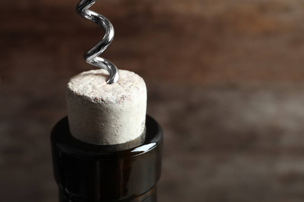 Opening bottle of wine with corkscrew on blurred background, closeup - Photo, Image