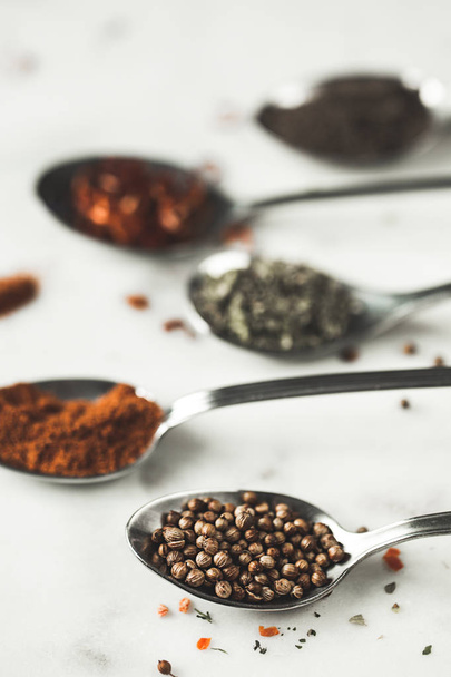 Spices in different spoons on stone marble table background. Rustic vintage color toning. - Fotoğraf, Görsel