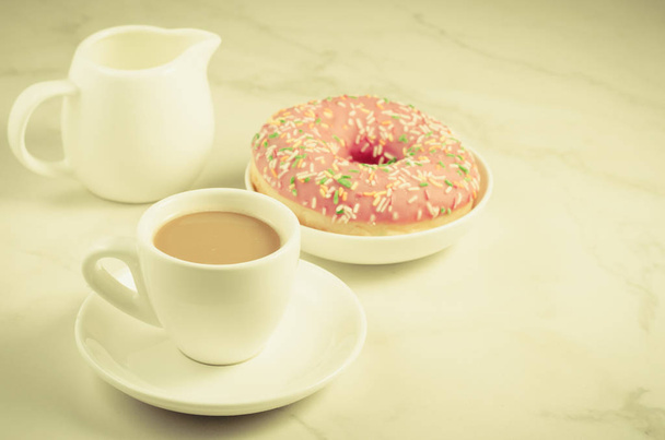 Coffee break: milk and fresh sugary pink donut/Coffee break: milk and fresh sugary pink donut on a white marble background. Selective focus and copyspace - Foto, Imagen