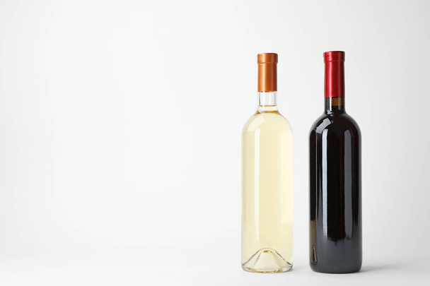Bottles of expensive red and white wines on light background - Фото, изображение