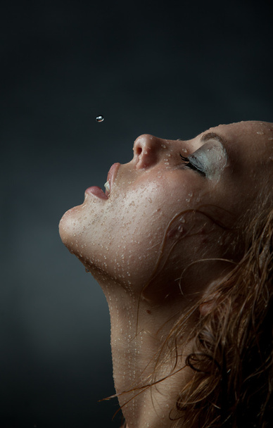 Portrait of a girl's face which water flows on a dark background. - Foto, afbeelding