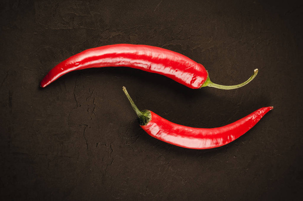 red hot Chile pepper on a dark stone/two red hot Chile pepper on a dark stone background. - 写真・画像