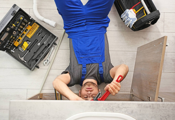Professional plumber with set of tools working indoors, top view - Photo, Image
