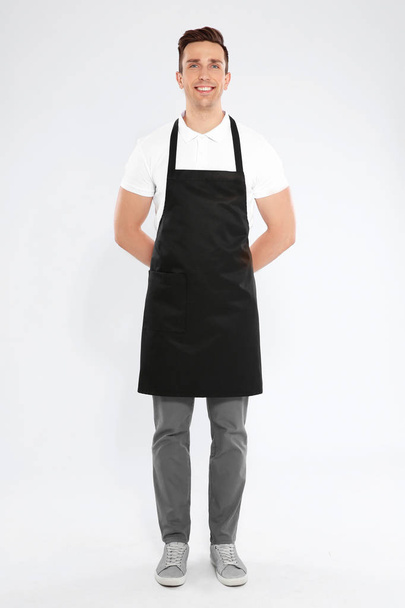 Full length portrait of handsome waiter in apron on light background - Photo, image