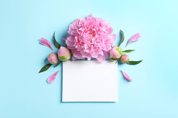 Beautiful peony flowers and blank card on color background - Foto, imagen
